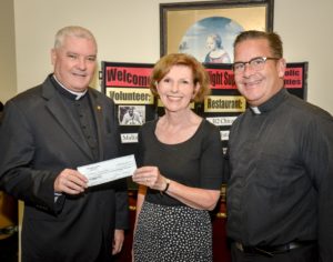 Eileen Larum, Board Member of the Chi-Town Jazz Festival presents a check to Catholic Charities, received by Msgr. Boland and Father Wayne at St. Vincent Center in Chicago.